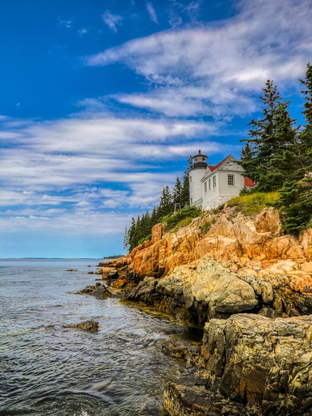 the ocean next to a cliff and lighthouse